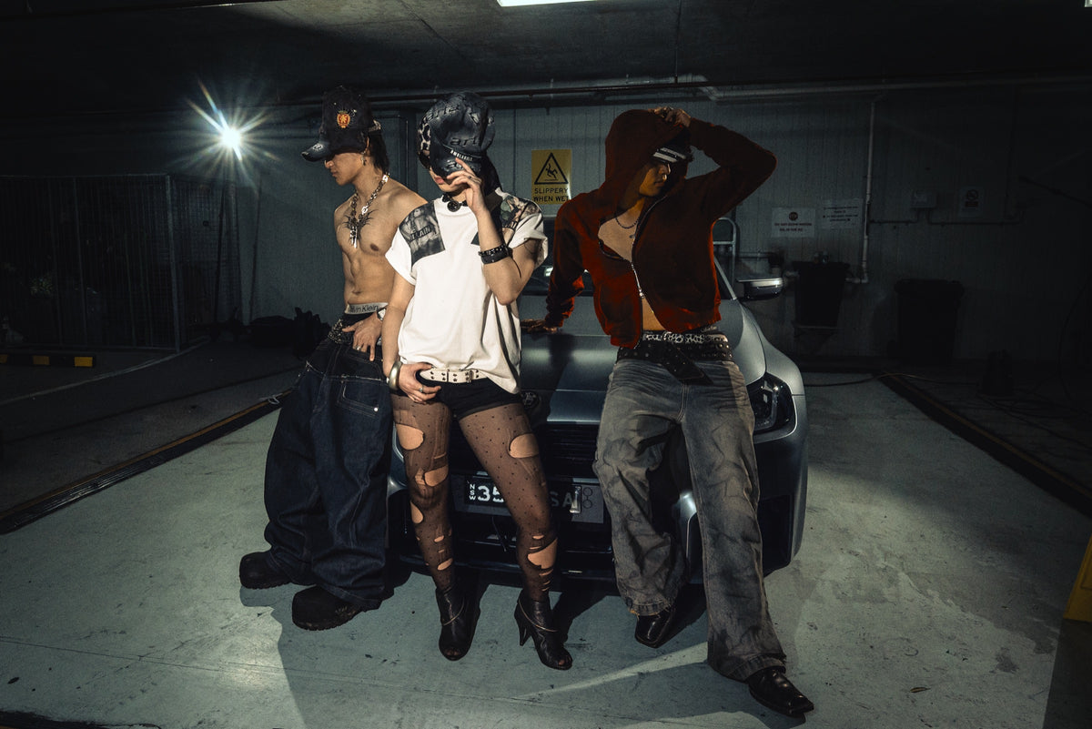Three models leaning on a grey BMW in an underground car park
